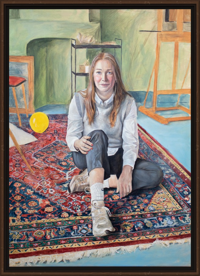 Portret in opdracht: een jonge vrouw zittend op een Perzisch tapijt in een atelier, met een ezel achter haar.